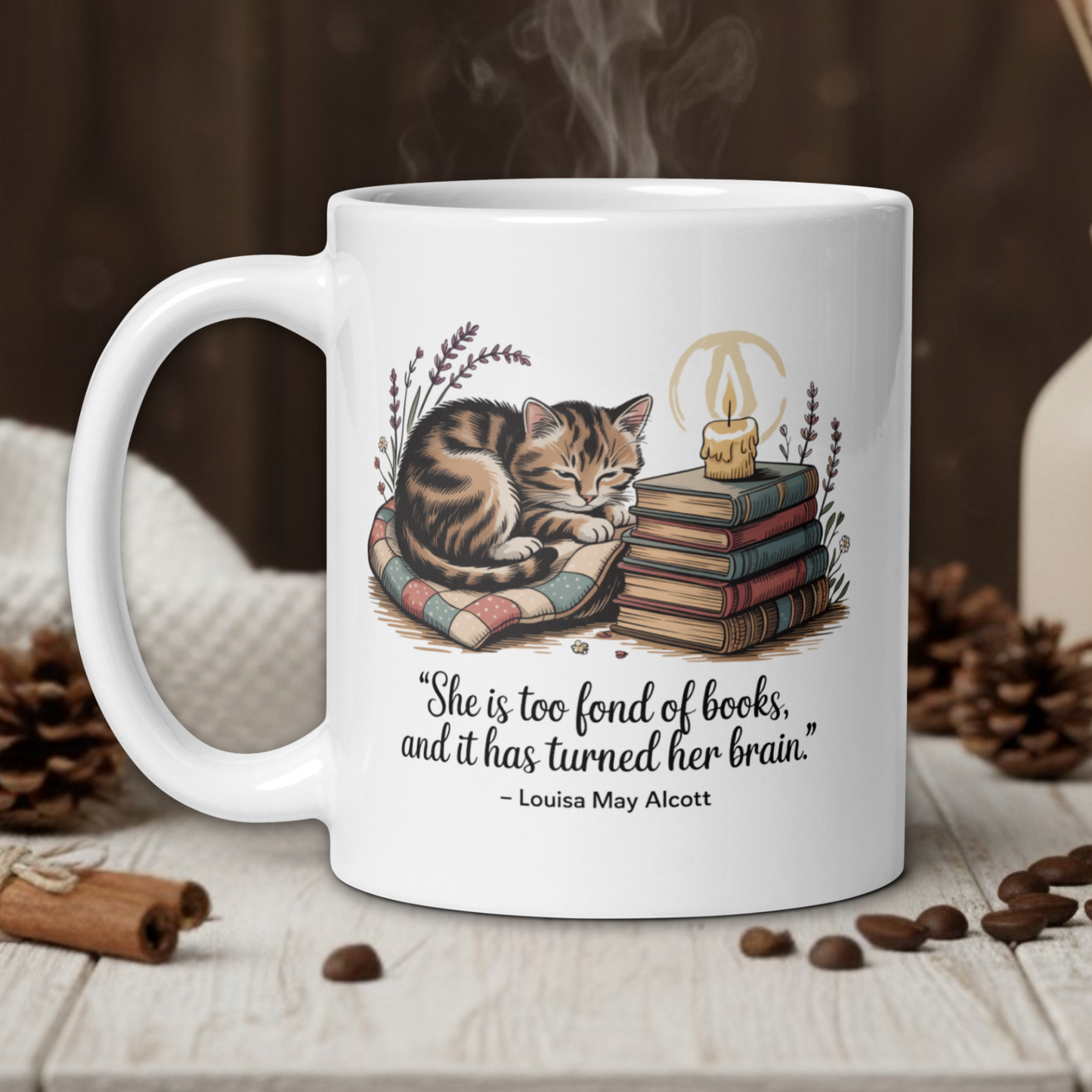 White mug with a cat illustration and quote on a wooden table with coffee beans and a vase in the background.