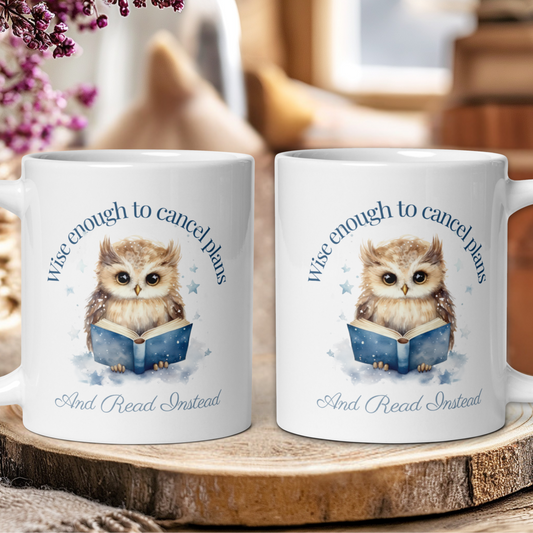 Two white mugs with an owl design and text on a wooden surface.