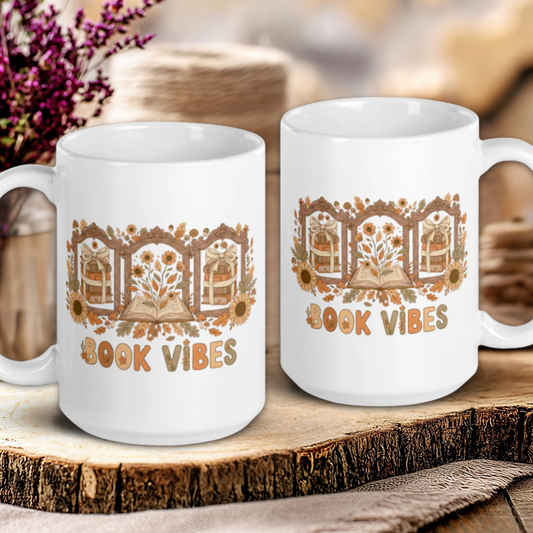 Two white mugs with 'Book Vibes' design on a wooden surface with a blurred background