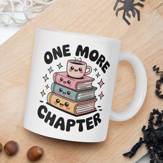 White mug with 'One More Chapter' design on a wooden board with books and nuts.