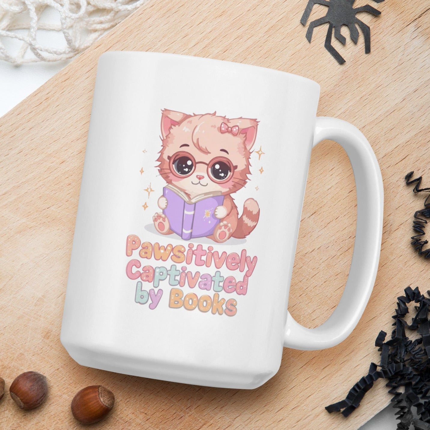White mug with a cat illustration and text on a wooden board with nuts and spider decorations.