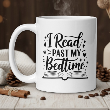 White mug with 'I Read Past My Bedtime' text on a wooden table with coffee beans and a vase in the background.