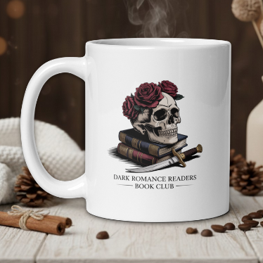 White mug with skull and roses design on a wooden table with coffee beans and a vase in the background.