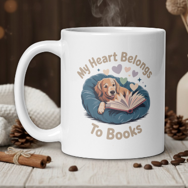 White mug with a dog reading a book design, text 'My Heart Belongs To Books', steam rising, on a wooden table.