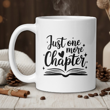 White mug with 'Just one more chapter' text on a wooden table with coffee beans and a vase in the background.