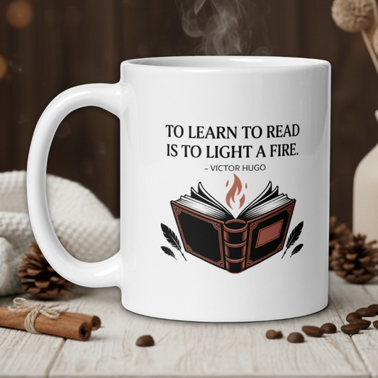 White mug with book design and quote on a wooden table with coffee beans and a vase in the background.