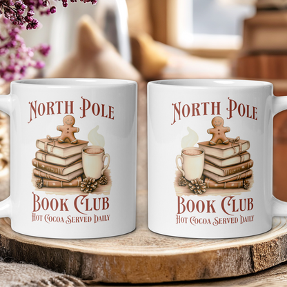 Two mugs with 'North Pole Book Club Hot Cocoa Served Daily' design on a wooden surface.