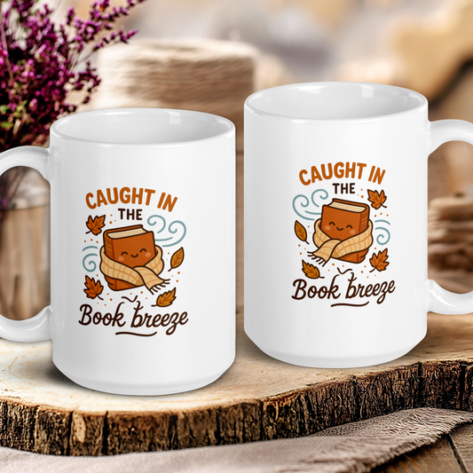Two white mugs with a cartoon bear and text 'Caught in the Book Breeze' on a wooden surface.