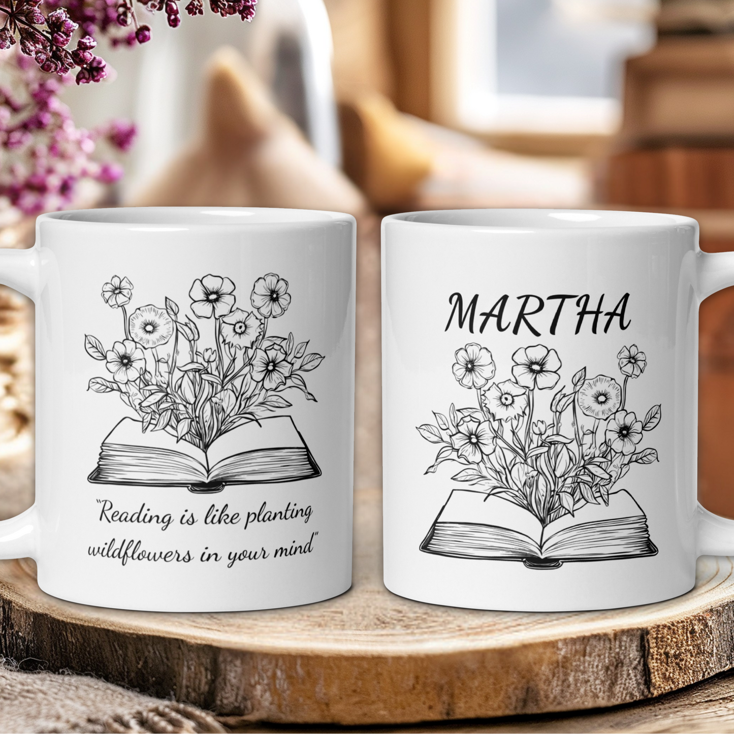 Two white mugs with floral and book design on a wooden surface