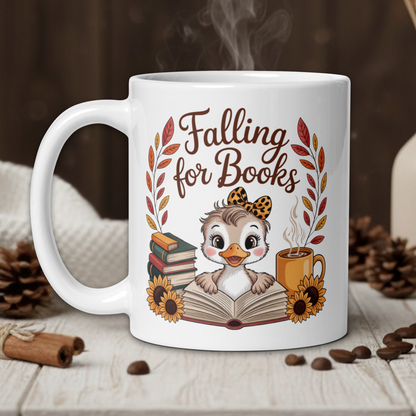 White mug with 'Falling for Books' design featuring a owl and books, on a wooden table with coffee beans and a vase in the background.