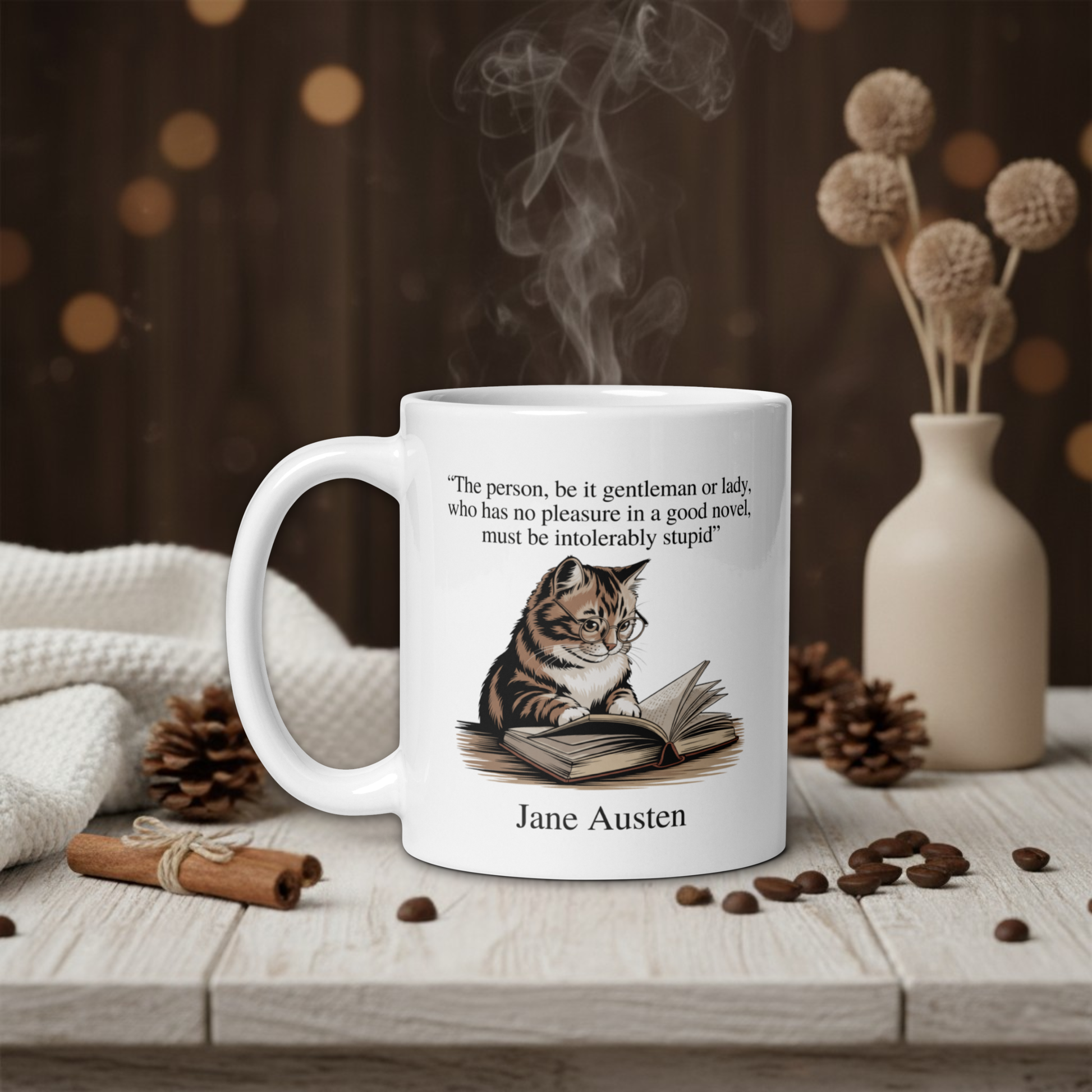 White mug with a cat illustration and Jane Austen quote on a wooden table with coffee beans and a vase in the background.