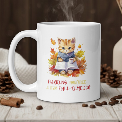 White mug with a cat illustration and text on a wooden table with coffee beans and a vase.
