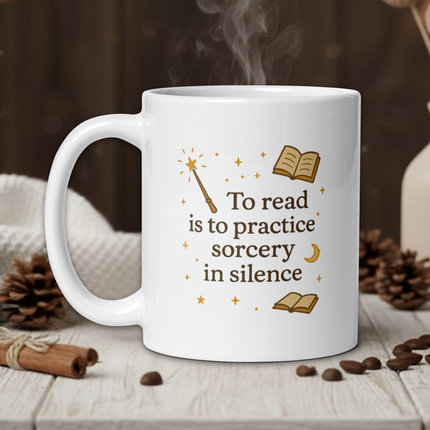 White mug with 'To read is to practice sorcery in silence' text on a wooden table with coffee beans and a vase in the background.