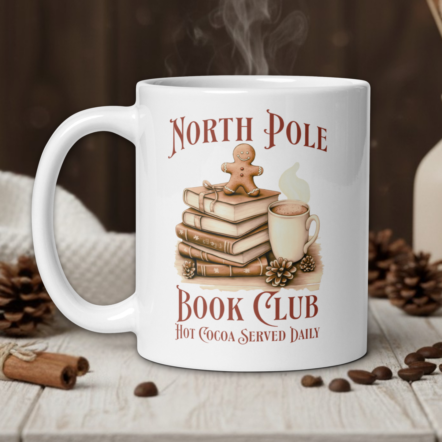 White mug with 'North Pole Book Club' design on a wooden table with coffee beans and a vase in the background.