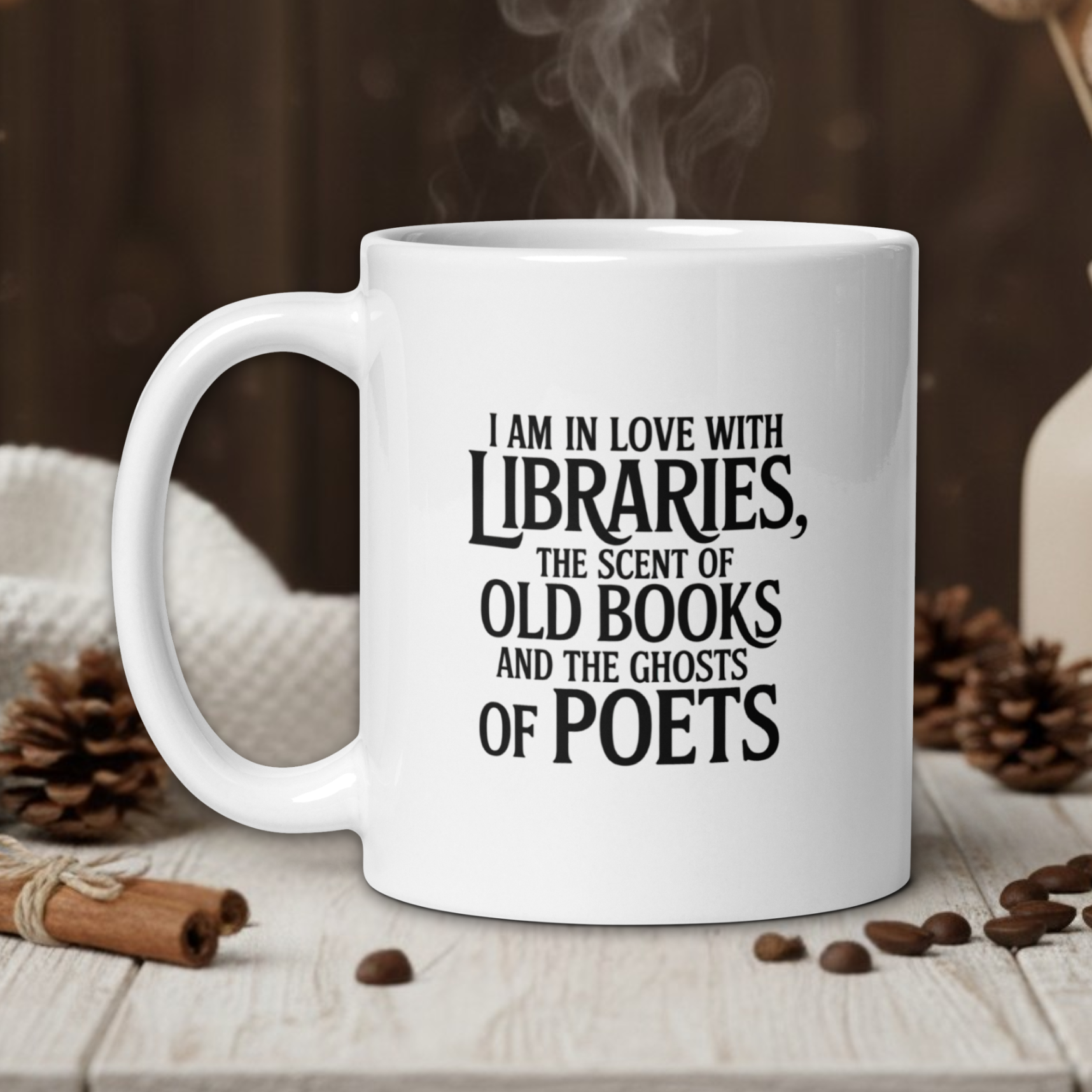 White mug with text on a wooden table with coffee beans and a vase in the background