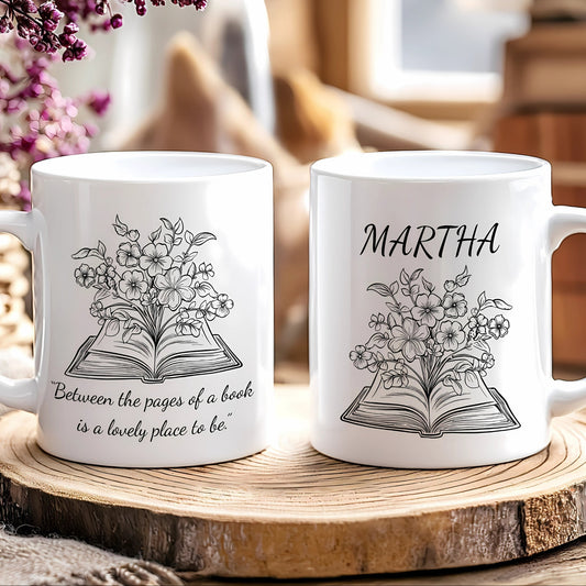 Two white mugs with floral and book design on a wooden surface