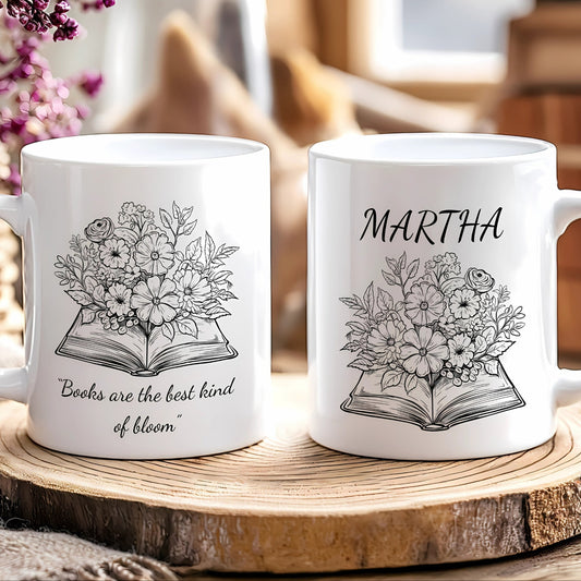 Two white mugs with floral and book design on a wooden surface