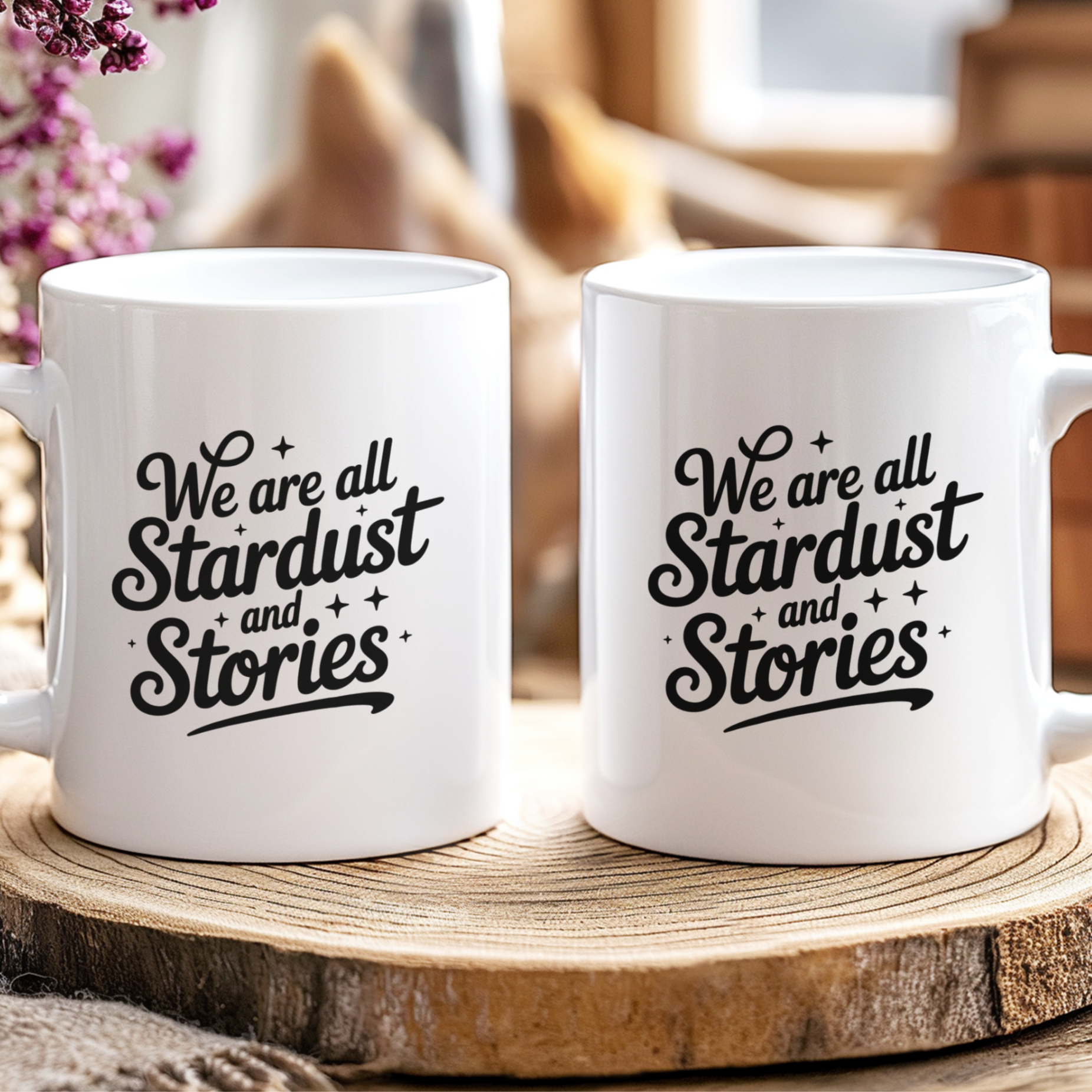 Two white mugs with 'We are all Stardust and Stories' text on a wooden surface.