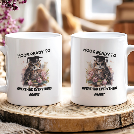 Two white mugs with an owl design and text on a wooden surface.