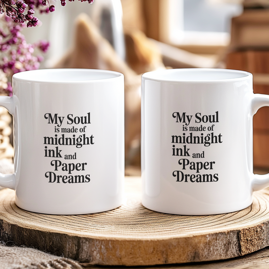 Two white mugs with text on a wooden surface with a blurred background