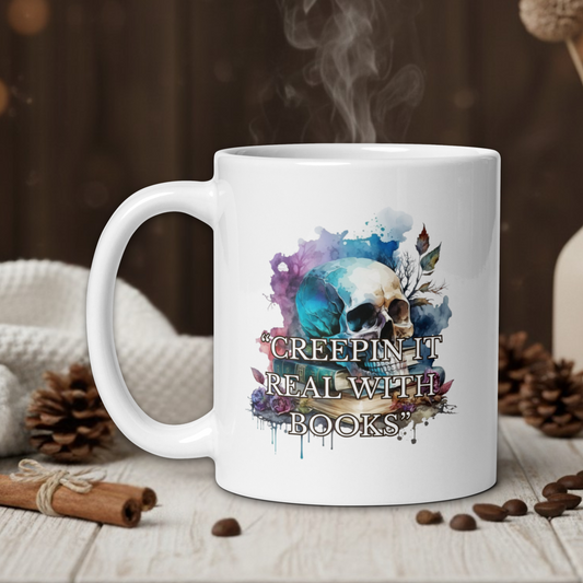 White mug with skull design and text on a wooden table with coffee beans and a vase in the background