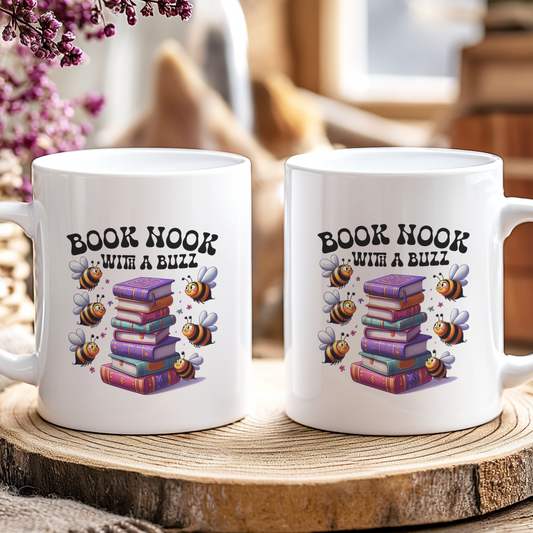 Two white mugs with 'Book Nook with a Buzz' design on a wooden coaster.