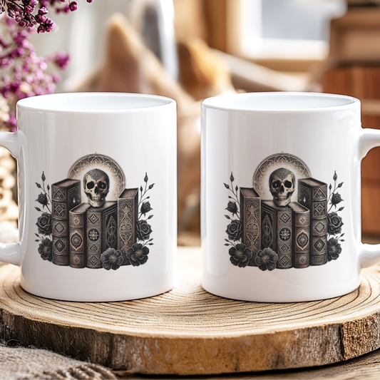 Two white mugs with skull and book design on a wooden coaster.