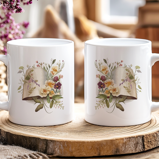 Two white mugs with floral designs on a wooden coaster, surrounded by flowers and a jar.