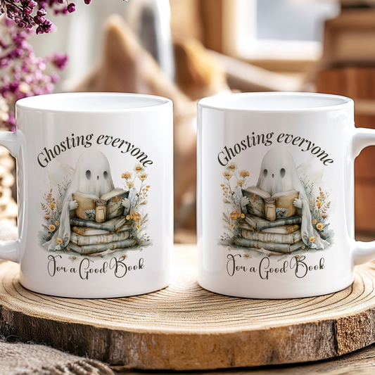 Two mugs with a ghost and book design on a wooden coaster with flowers and jars in the background.