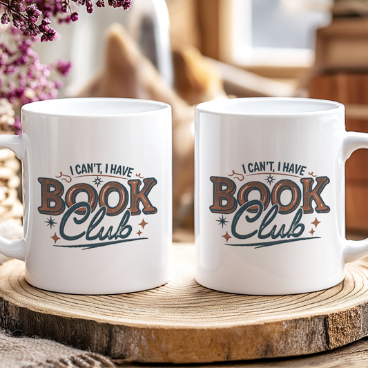 Two white mugs with 'I can't, I have Book Club' text on a wooden coaster.