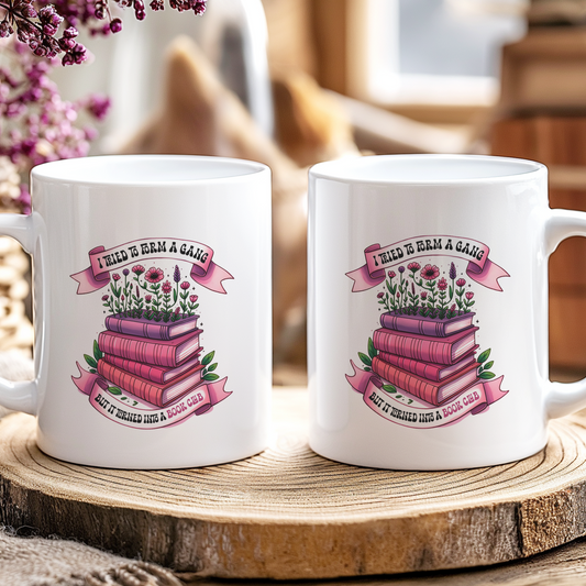 Two white mugs with floral book design and text on a wooden coaster.