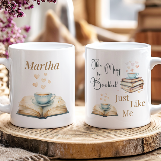 Two white mugs with book-themed designs on a wooden surface.
