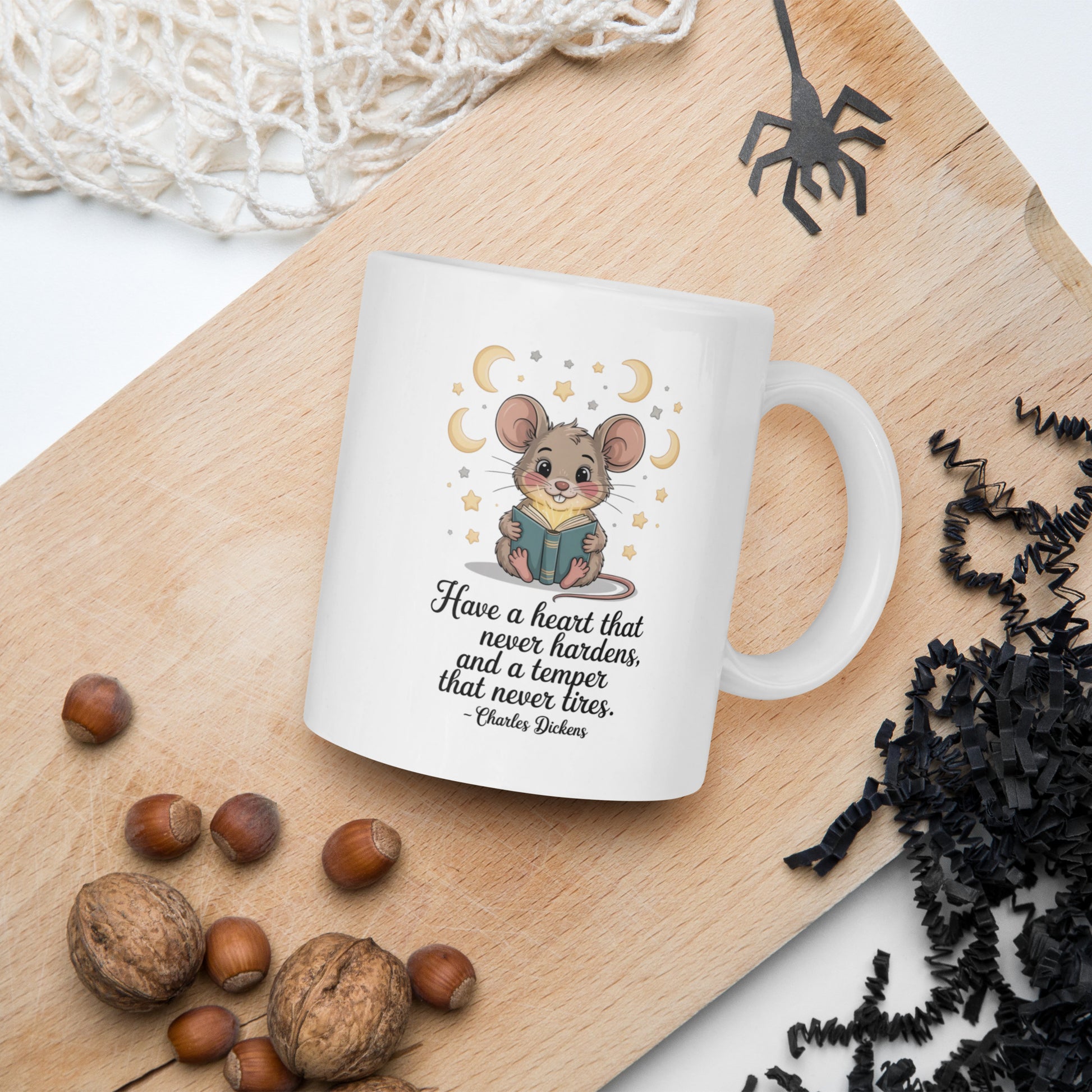 White mug with a mouse illustration and text on a wooden board with nuts and spider decorations.