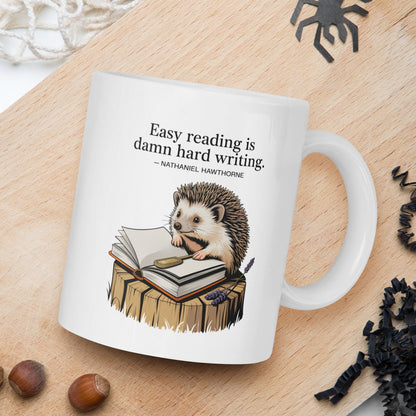 Mug with hedgehog illustration and quote on a wooden board with nuts and spider decorations.