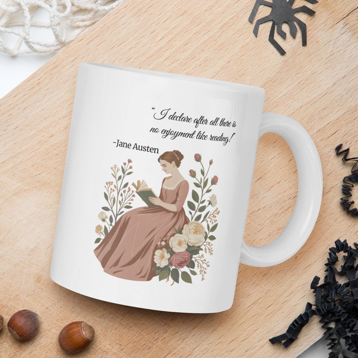 White mug with Jane Austen quote and illustration on a wooden board with nuts and spider decorations.